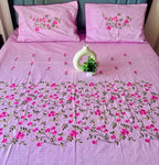 Pink floral bedspread with matching pillows on a bed.