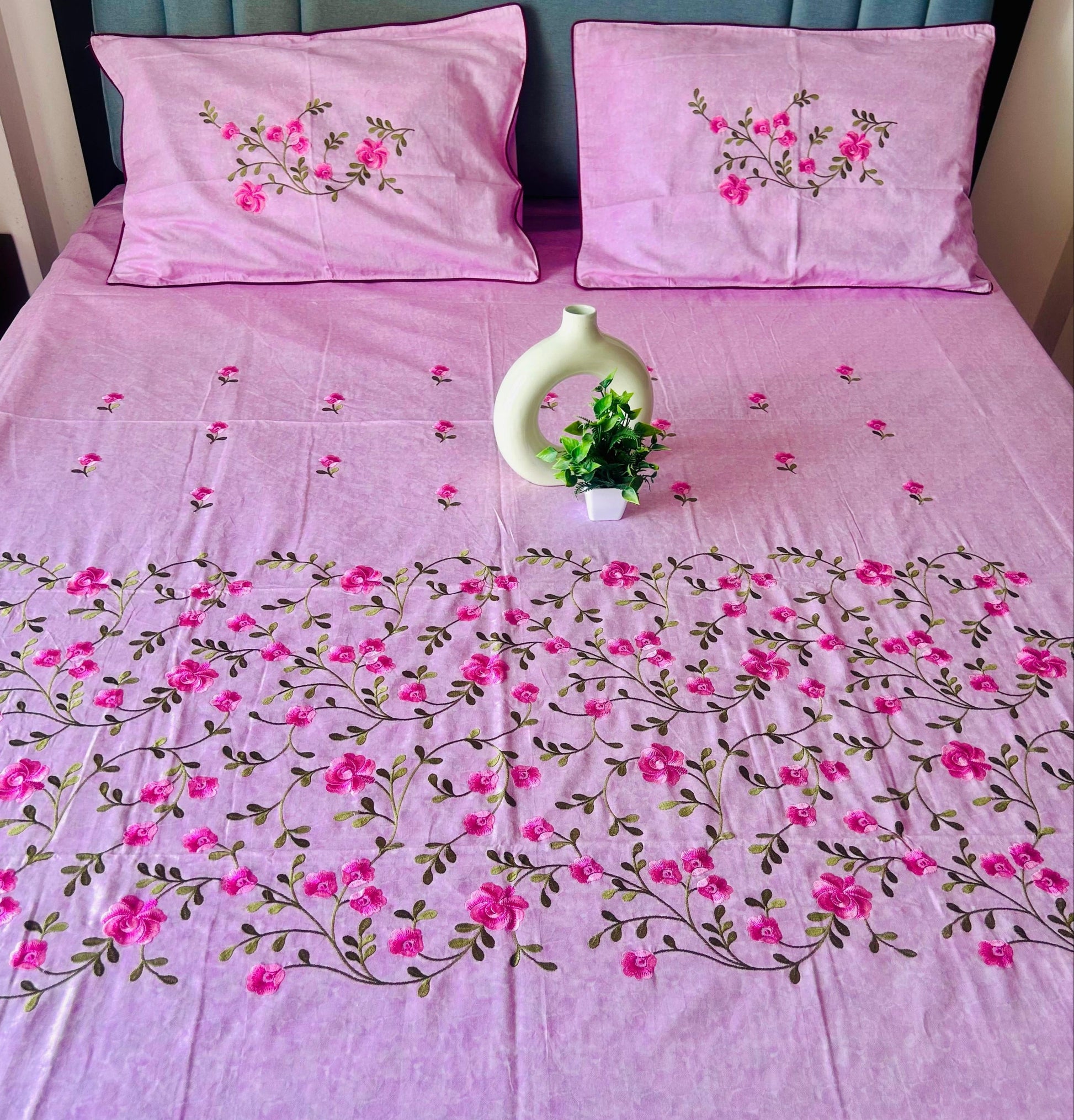 Pink floral bedspread with matching pillows on a bed.